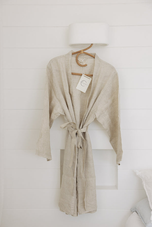 Linen Label Natural Oat Linen Bathrobe Kimono Robe hanging on a detailed cane hanger - looking luxurious, perfect for ultimate comfort and relaxation. Crafted with 100% French Linen showing the waist time and robe mid length