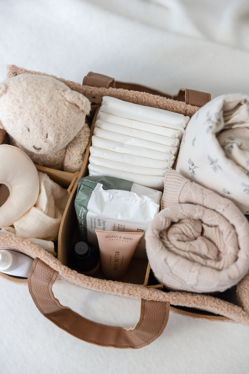 Line Label Tan chocolate caramel caddy showing the dividers filled with all your baby necessities, baby wipes, baby cream, baby wrap, muslin wrap, teddy, nipple cream, snuggle toy and nappies. 