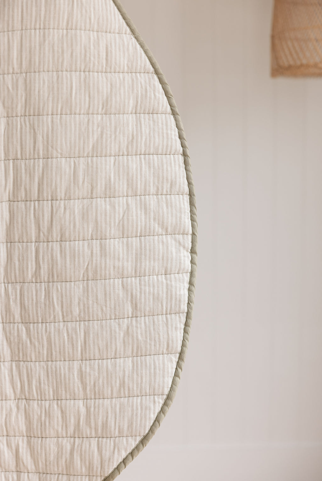 Linen label Play mat close up photo showing the reversible side colour pinstripe and sage green binding as well as showing the quilting detail and high quality of the mat