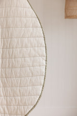 Linen label Play mat close up photo showing the reversible side colour pinstripe and sage green binding as well as showing the quilting detail and high quality of the mat