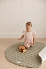 Baby toddler playing with a wooden truck playing on Linen Label Pure French Linen quilted padded play mat. The mat edge is folded showing both sides, one soft sage green colour and the other natural pinstripe colour