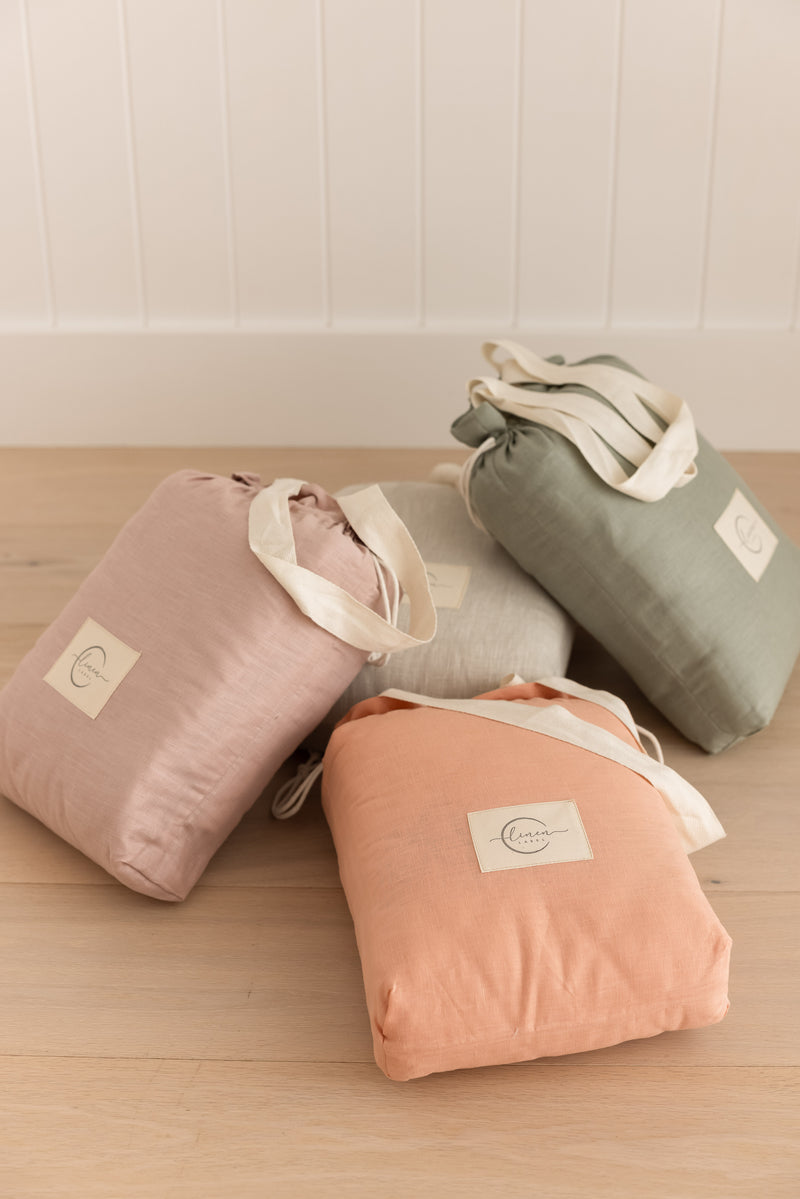 Linen Label quilted play mats packed in the carry bags in all colours, Peach, gingham, sage green, Dusty Rose Pink, nayural Oat