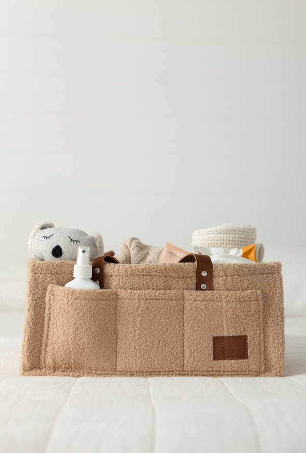 Portable organiser for changing essentials, perfect for nursery, car, or hospital use. Features 6 pockets, 5 removable dividers for organised storage. Move seamlessly around the home, ideal for on-the-go parents with extra storage pockets. Convenient for overnight stays, picnics, with chocolate colour handles and snow teddy fabrichandles for easy transport. Neutral boucle material, easy-to-clean felt, and vegan leather. Size: 40cm x 28cm x 18cm. Ivory/cream with chocolate vegan leather straps.