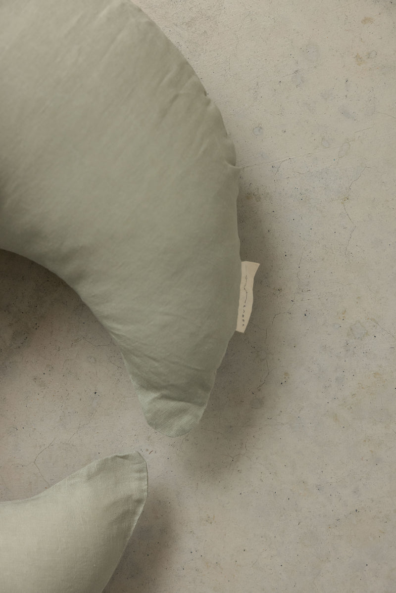 Close up photo showing the detail of Linen Label new pure french Flax Linen nursing pillow in baby pink. design in the new moon shape.