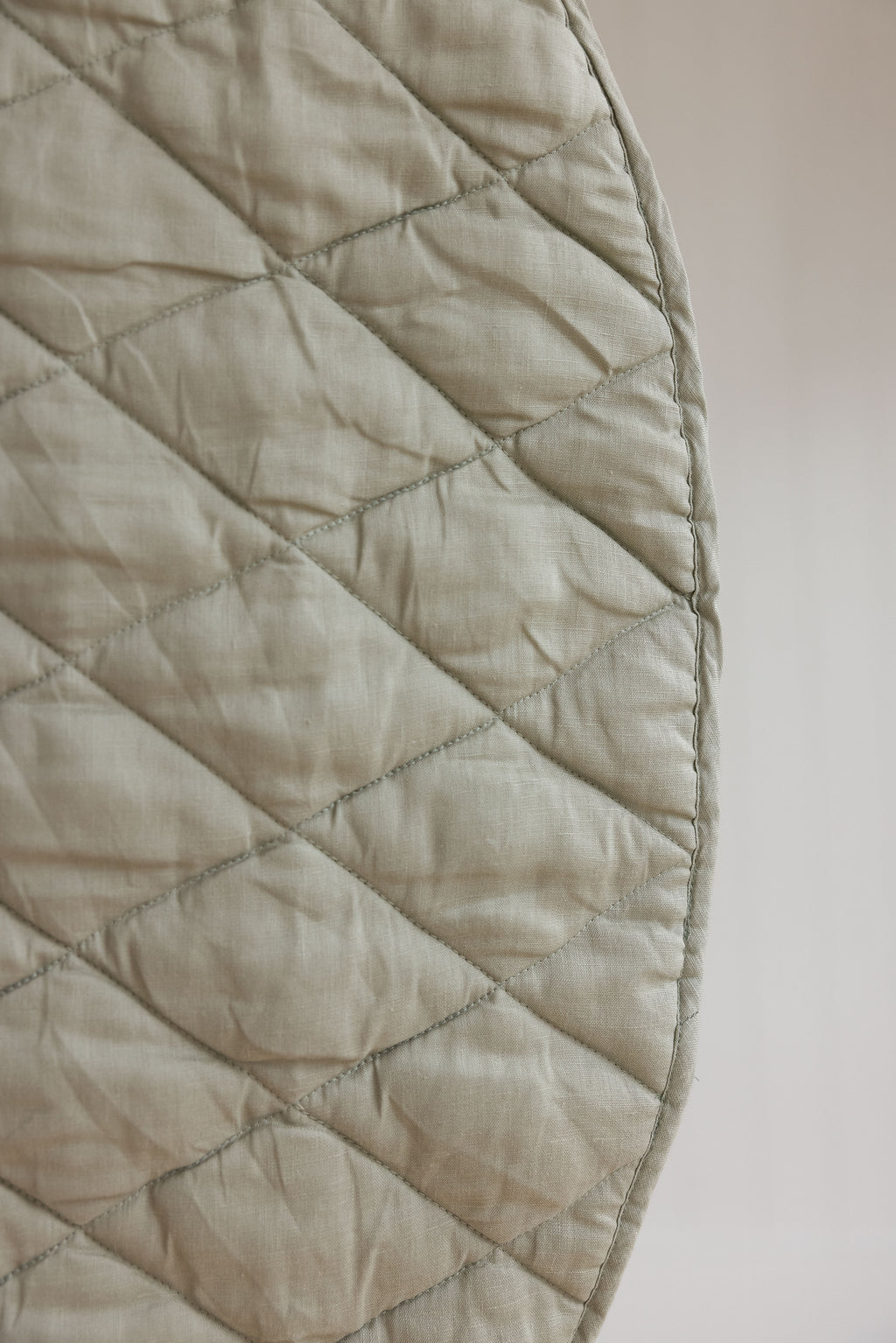 Linen label logo featured on the play mat showing close-up photo of the main side in soft sage as well as showing the quilting detail and high quality of the mat