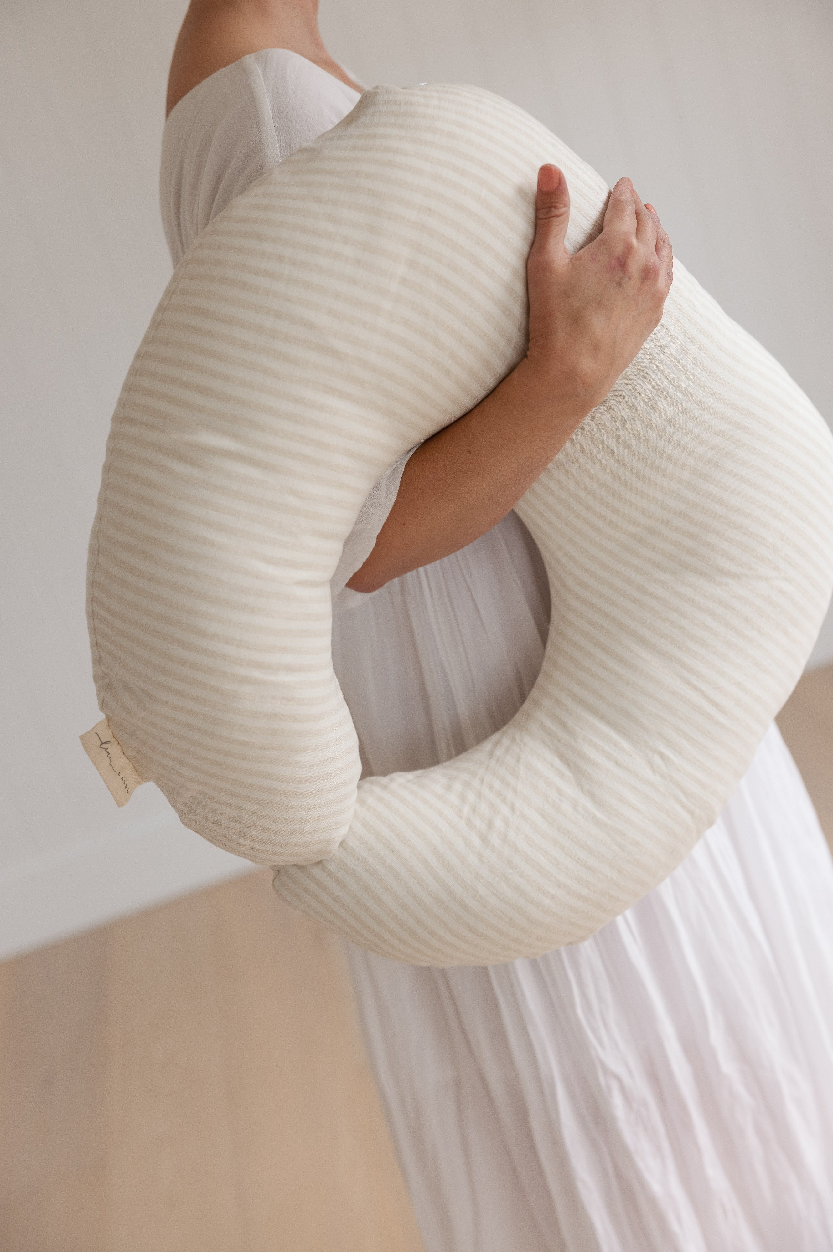 Linen Label Nursing pillow with mother holding the pillow showing the plush size and shape of the pillow