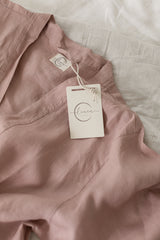 Linen Label Dusty Rose Pink French Linen Bathrobe Kimono Robe draped on the bed with Linen Label logo showing - looking luxurious and aesthetically pleasing in a Dusty Rose, perfect for ultimate comfort and relaxation. Crafted with 100% French Linen that grows softer with each wash