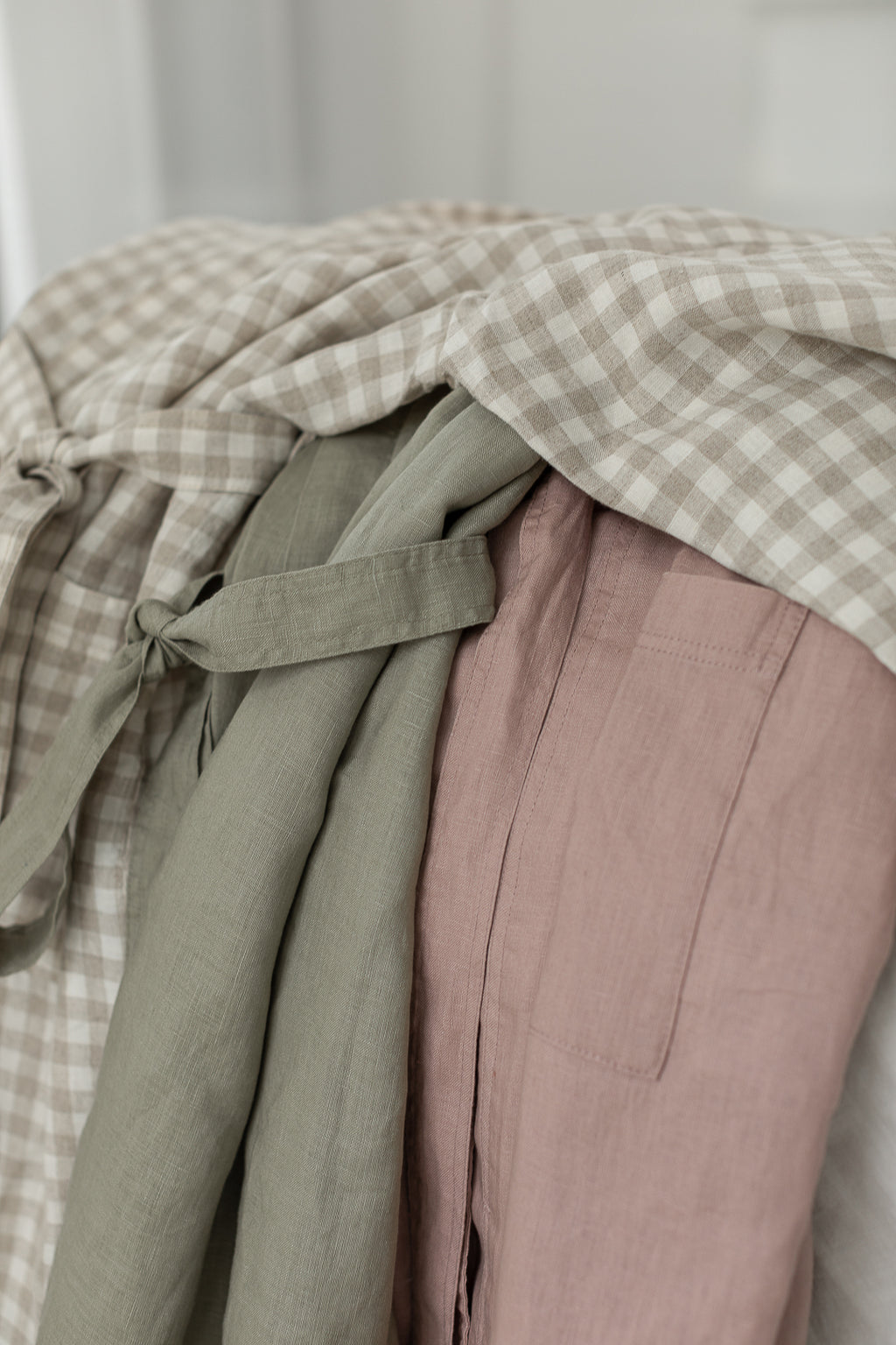 Linen LabelBathrobe Kimono Robe draped on the bed showing all the beautiful colours together, Dusty Rose Pink, Natural Oat Gingham, Soft Sage Green all inultimate comfort and relaxation. featuring the craftsmanship with 100% French Linen t